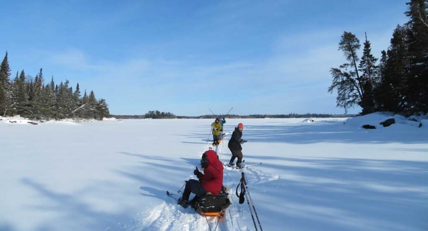 A group of people rest from skiing in a vast snowy landscape.